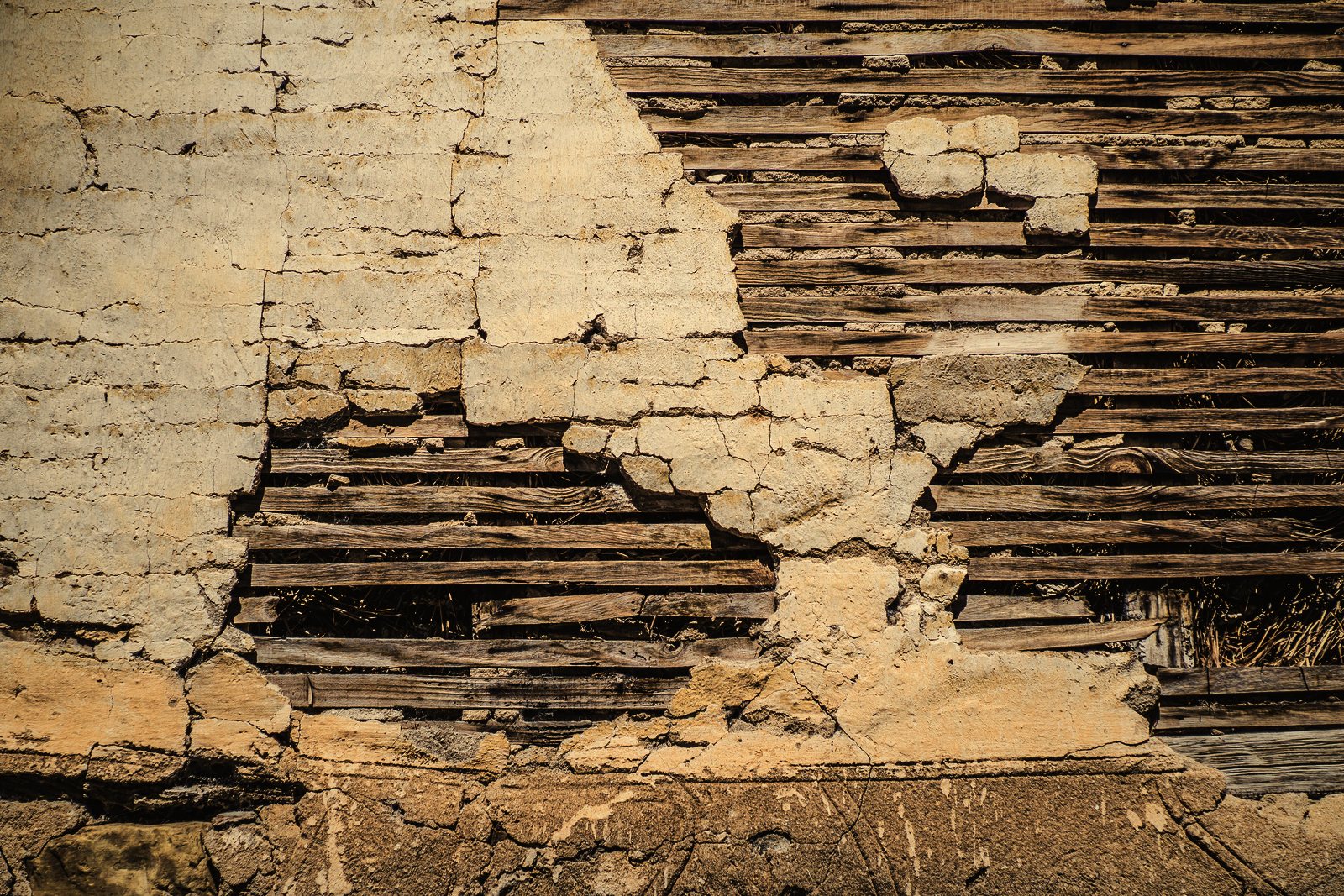 Enduit en terre écaillé laissant voir le lattis de bois qui le soutient, photo d'illustration
