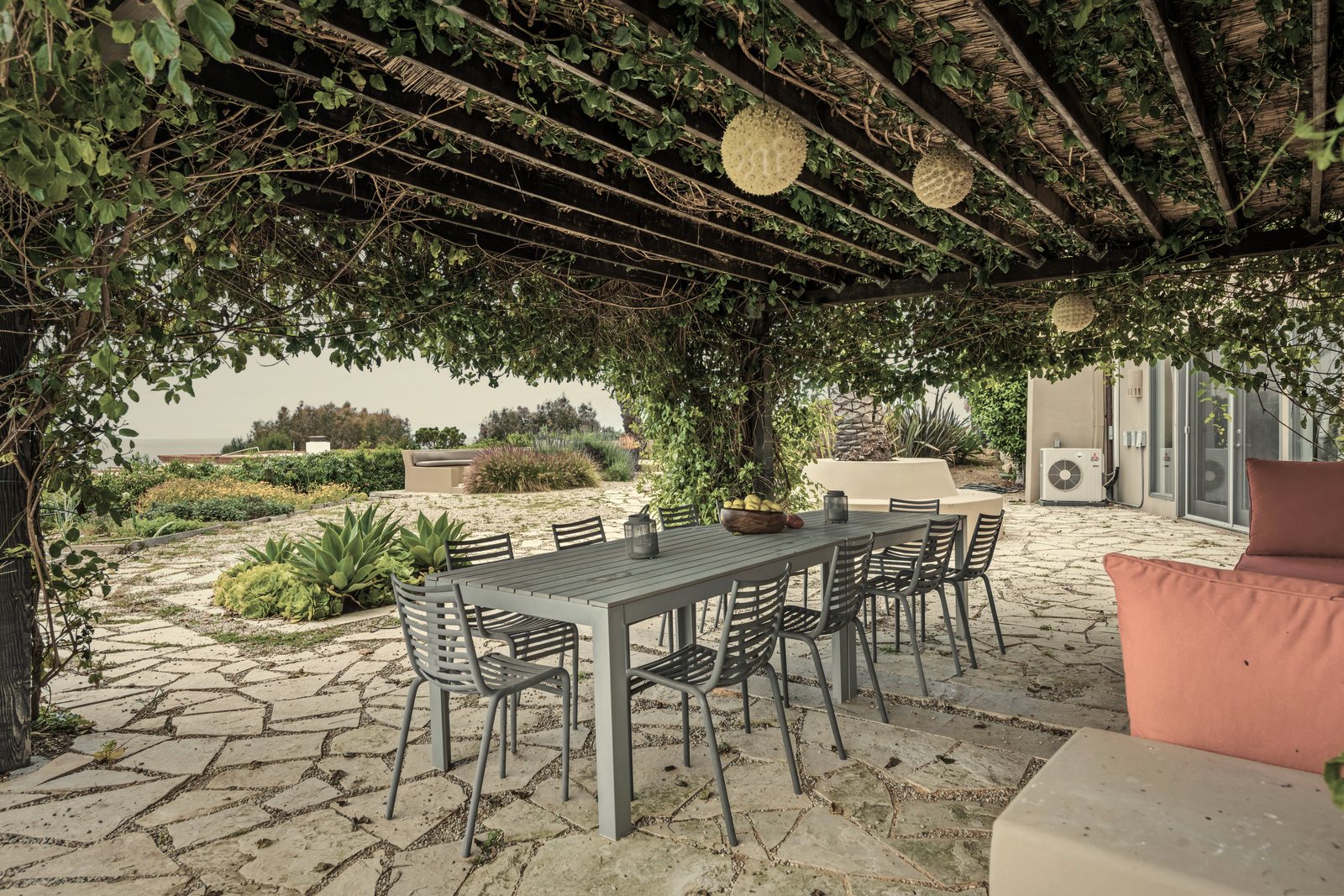 Terrasse dallée de pierre sous une treille végétale, ouverte sur un jardin sec, photo d'illustration
