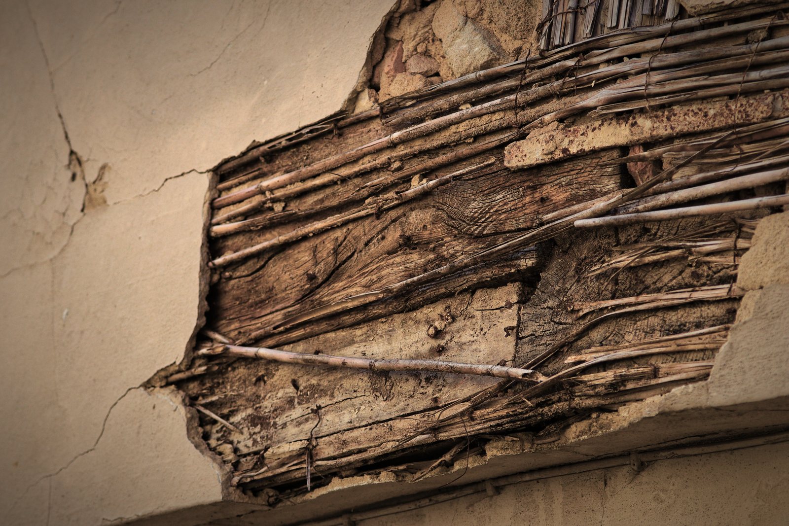 Mur dont l'enduit arraché laisse voir le lattis de bois et le remplissage en terre, photo d'illustration