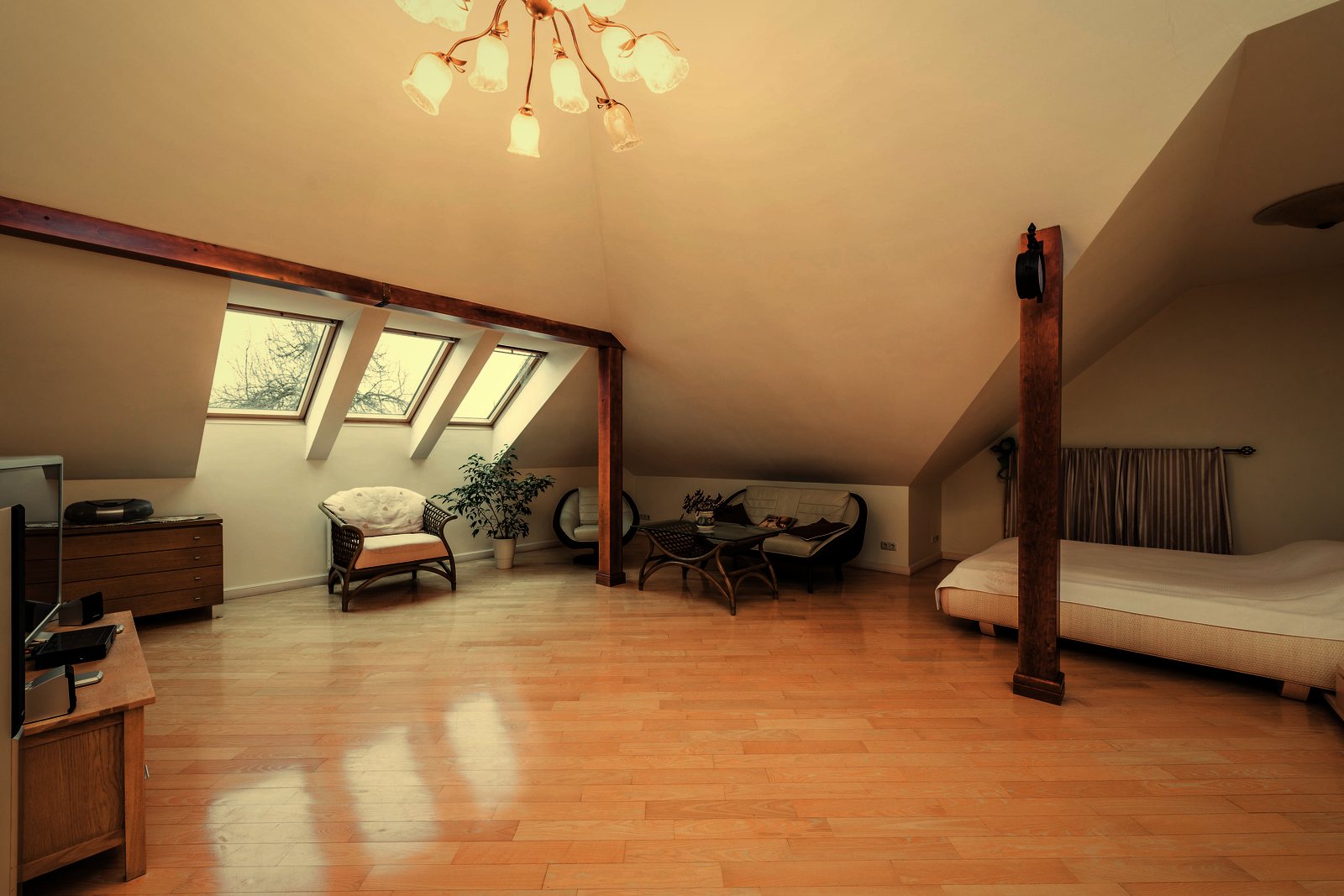 Comble aménagé lumineux avec poteau et poutre en bois, fenêtres de toit et parquet clair, photo d'illustration