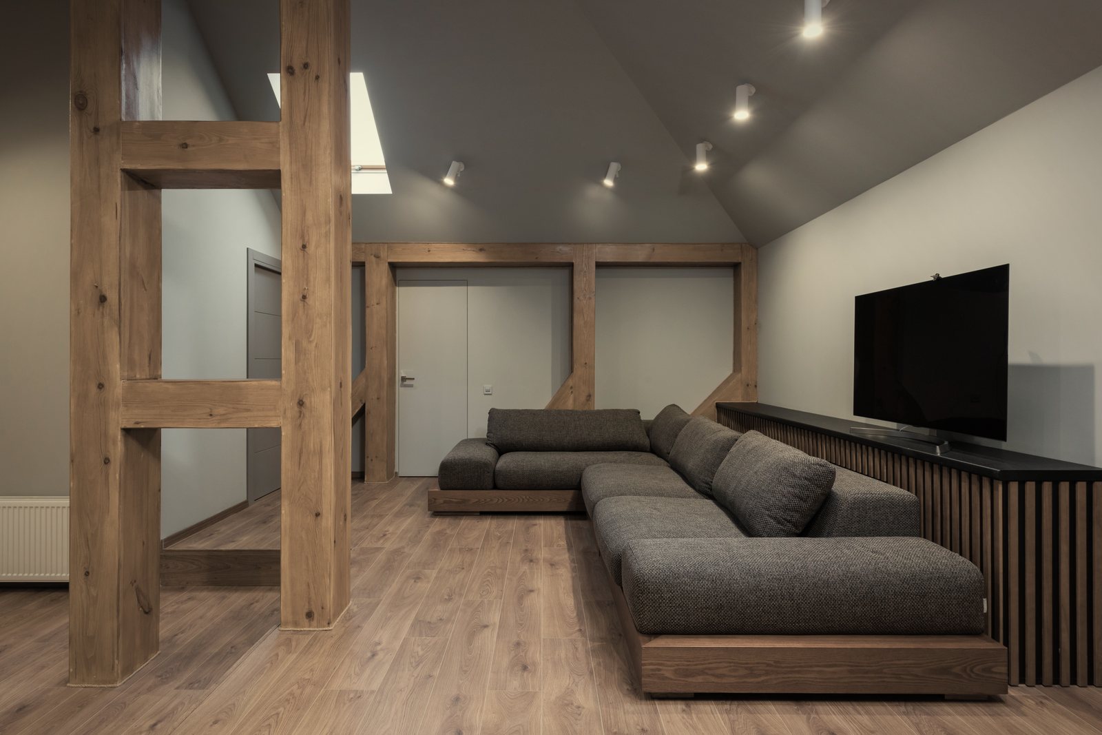 Poteaux et traverses en bois massif structurant un séjour contemporain aux murs clairs, photo d'illustration