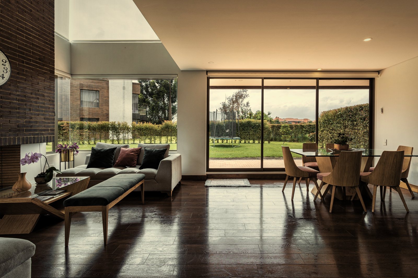 Séjour lumineux à parquet sombre ouvert sur le jardin par de grandes baies coulissantes, photo d'illustration