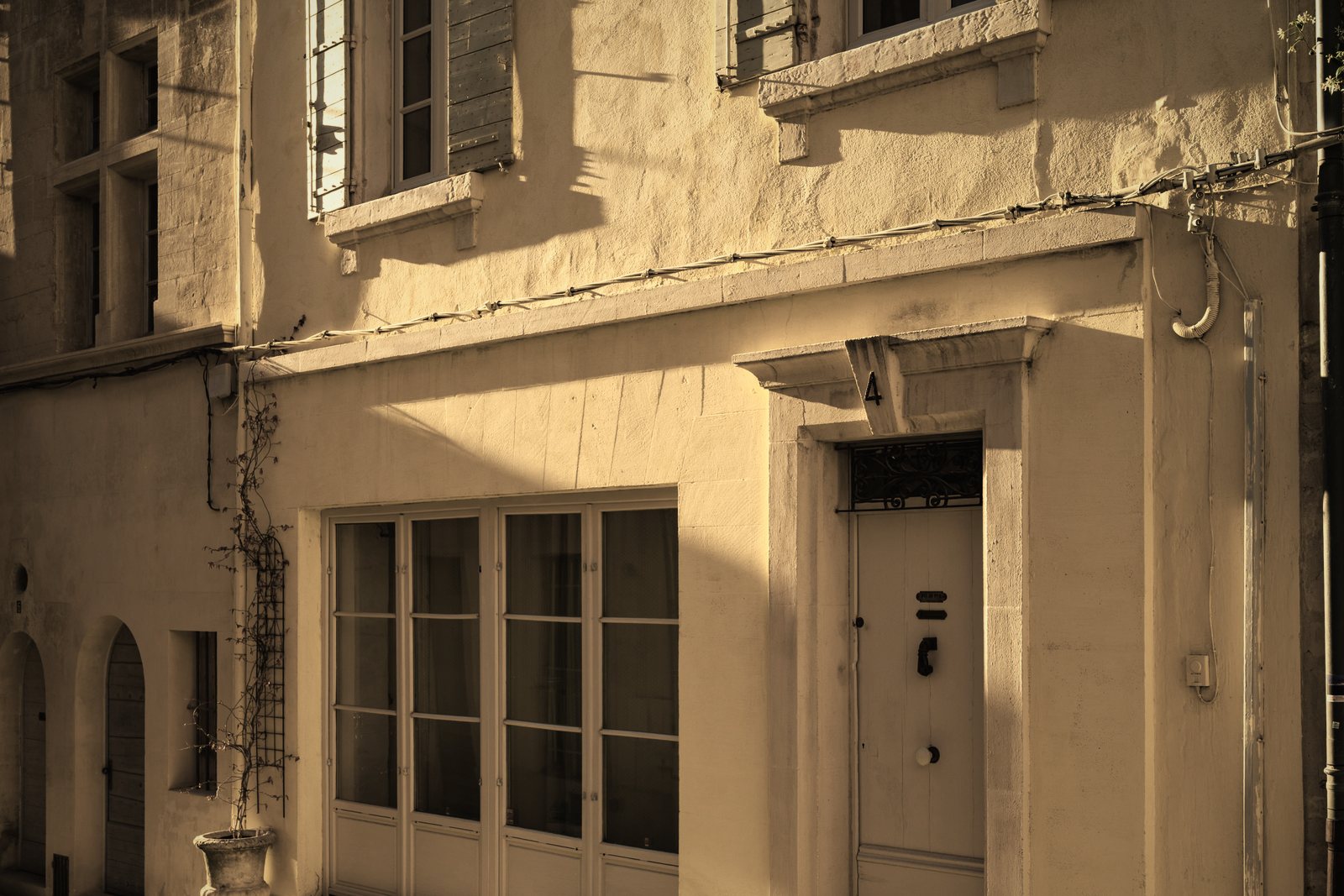 Rez-de-chaussée d'une maison de ville ancienne à façade enduite ocre, porte moulurée et grande vitrine, photo d'illustration
