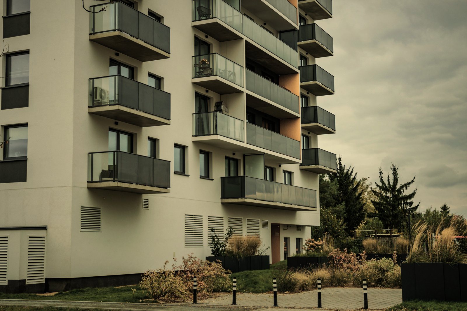 Immeuble collectif récent à façade blanche, balcons vitrés en saillie et jardin planté au pied, photo d'illustration