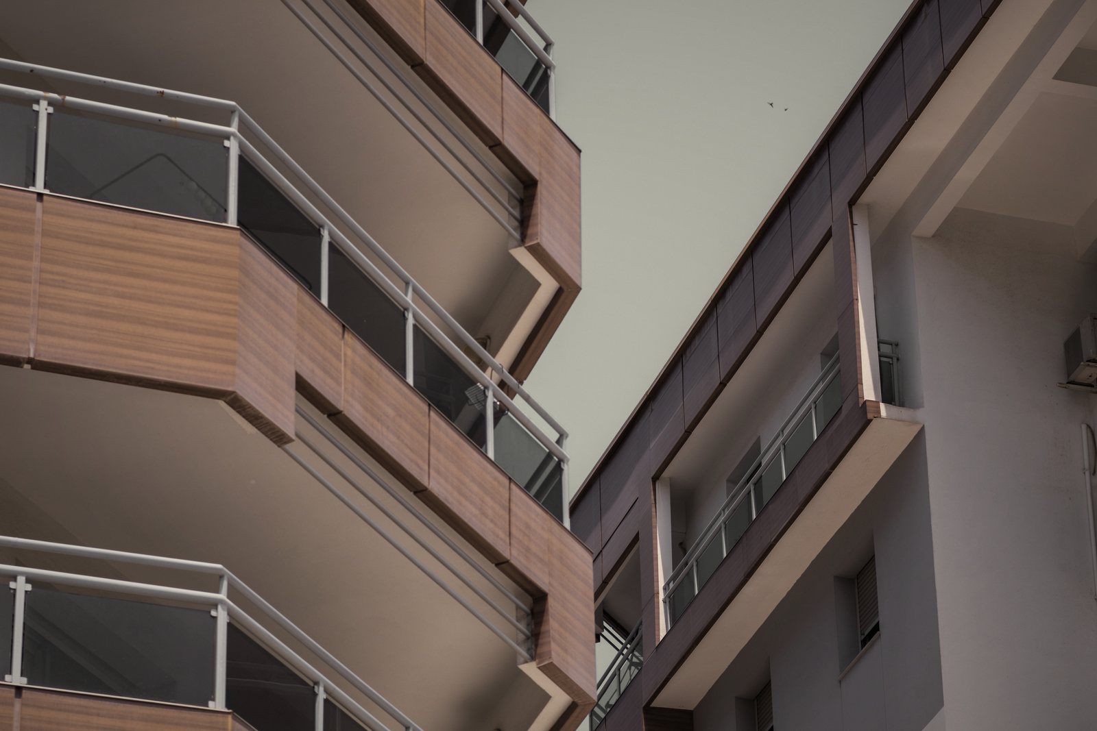 Balcons arrondis à garde-corps vitrés et parement bois vus en contre-plongée, photo d'illustration