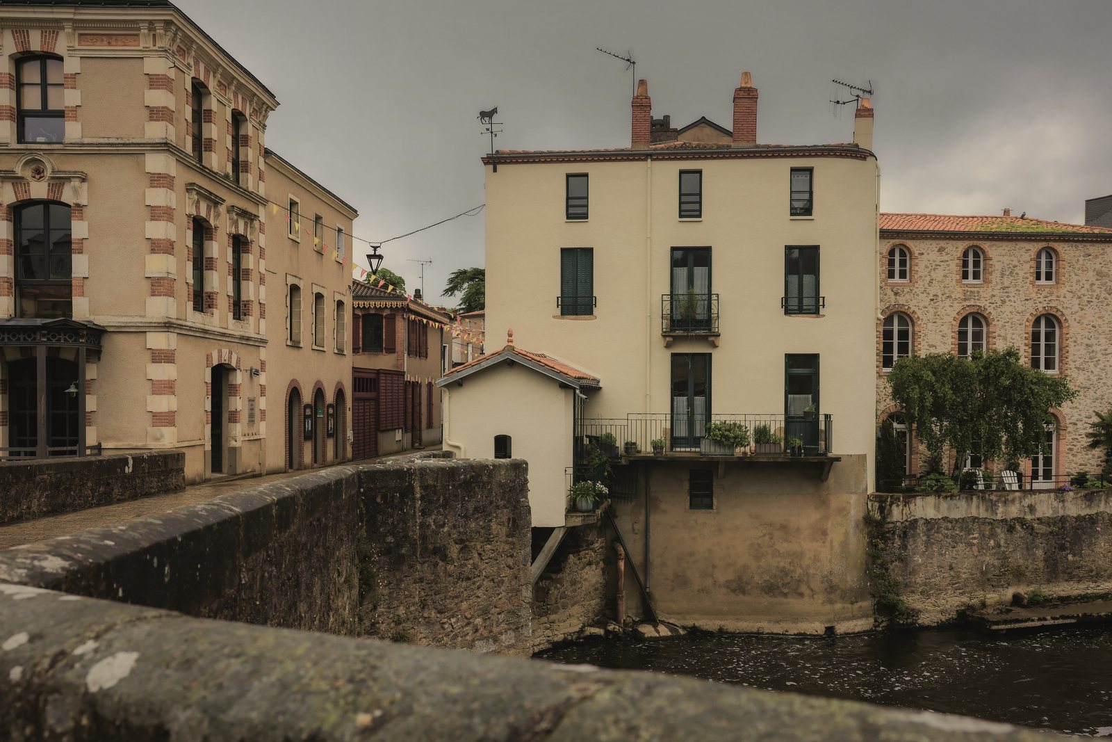 Maisons et petit immeuble au bord d'une rivière, murs de soutènement en pierre au premier plan, photo d'illustration