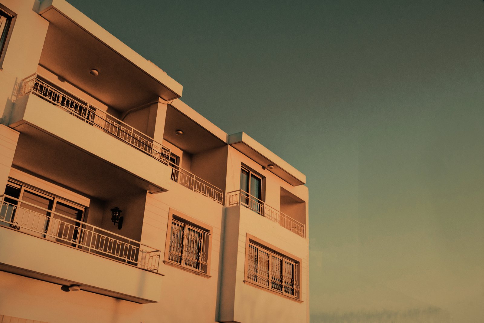 Immeuble de logements à balcons en retrait successifs, garde-corps fins, lumière chaude de fin de journée, photo d'illustration