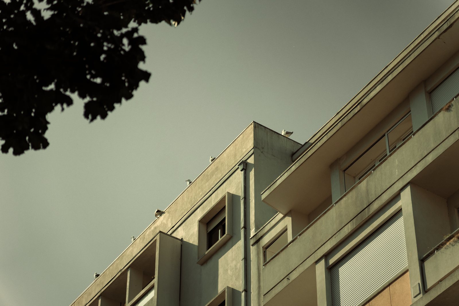 Balcons en saillie sur la façade claire d'un immeuble de logements, vus en contre-plongée, photo d'illustration
