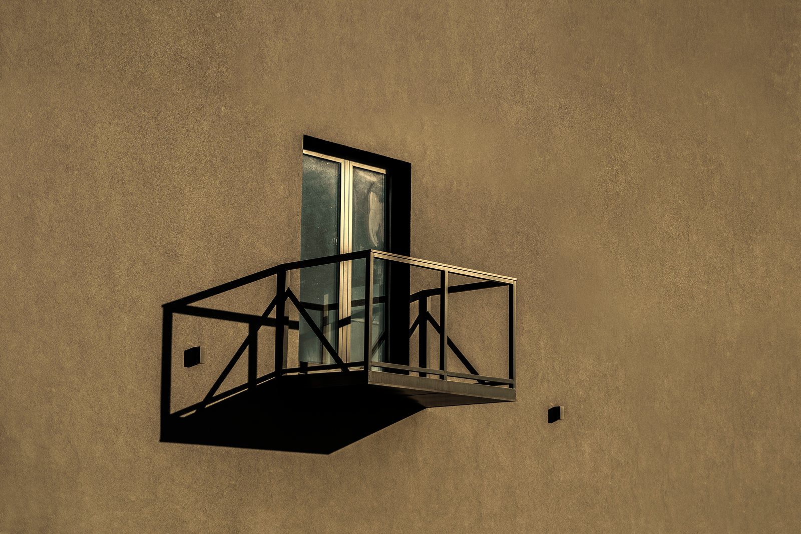 Balcon métallique isolé en porte-à-faux sur un mur enduit beige, avec porte-fenêtre, photo d'illustration