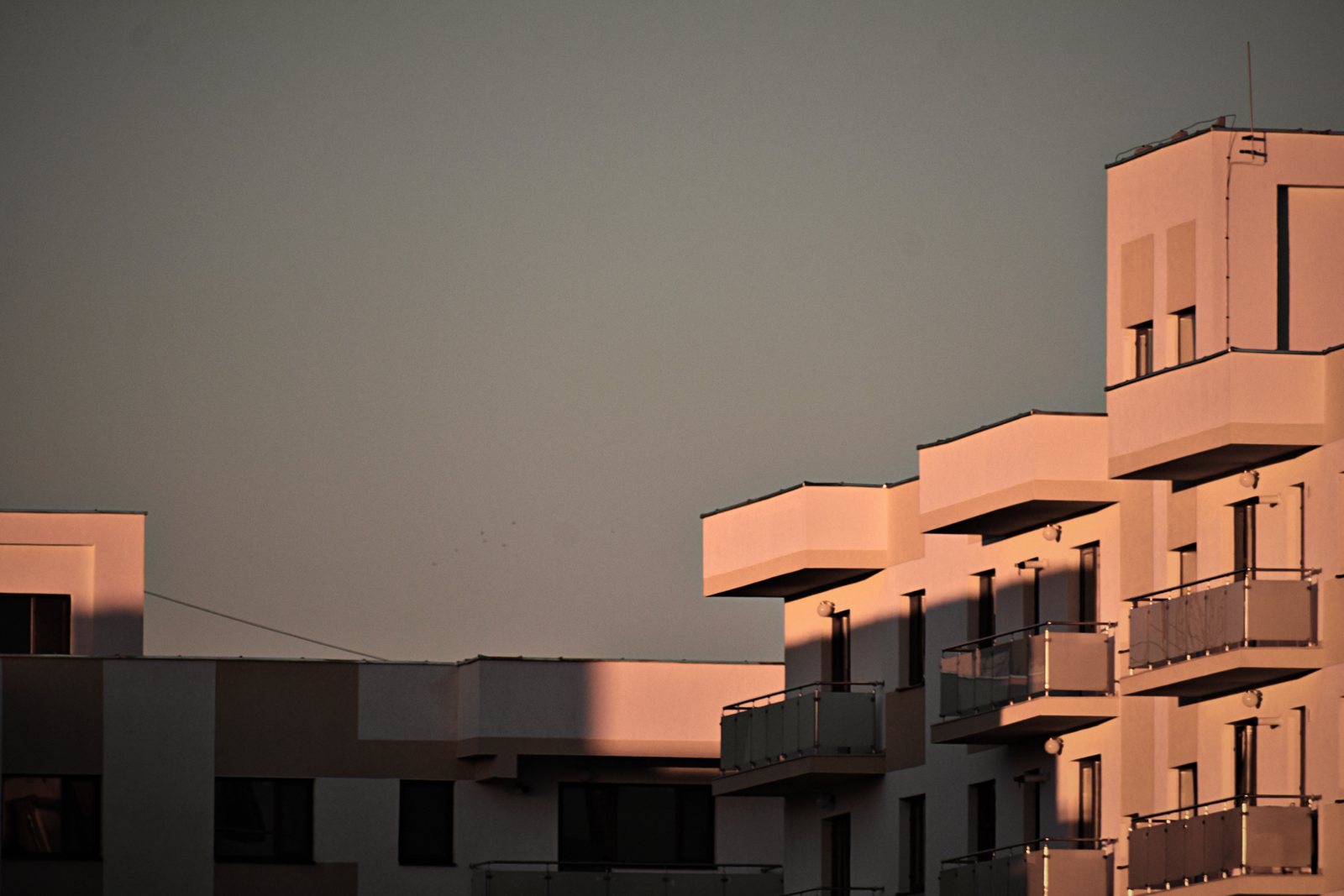 Volumes décalés d'un immeuble de logements rose à balcons en saillie, dans la lumière du soir, photo d'illustration