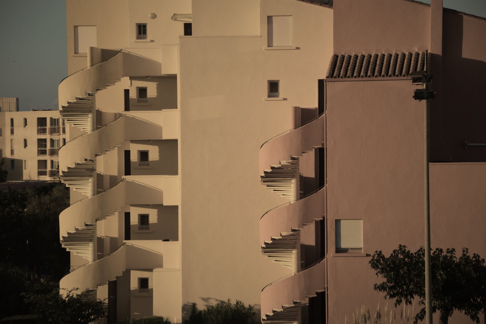 Façades ocre à balcons arrondis en gradins, ombres profondes de fin de journée, photo d'illustration