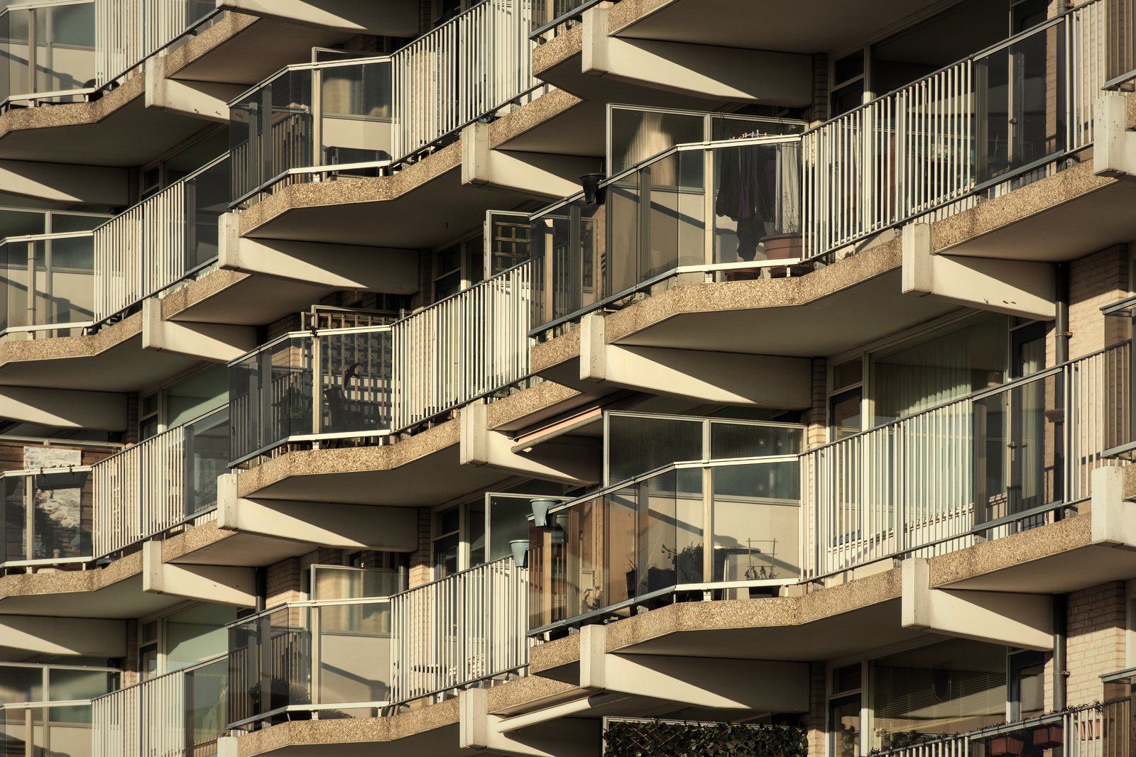 Balcons filants à garde-corps blancs et vitrages, rythmant une façade d'immeuble de logements, photo d'illustration