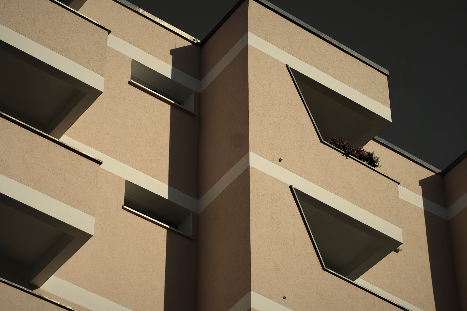 Balcons triangulaires en saillie sur une façade enduite beige soulignée de bandeaux clairs, photo d'illustration