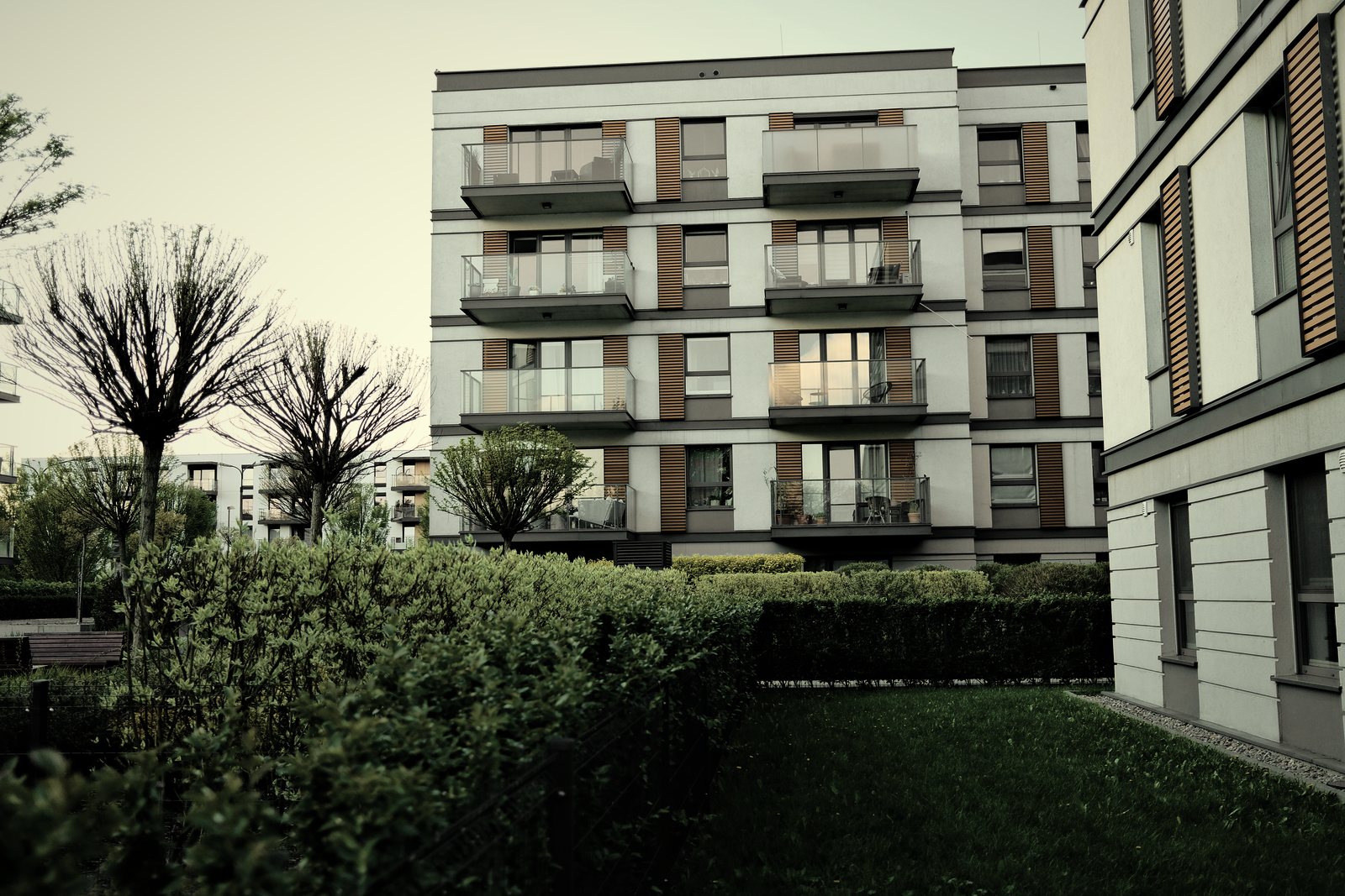 Petit immeuble de logements récent à balcons, précédé d'une haie et d'une pelouse, photo d'illustration