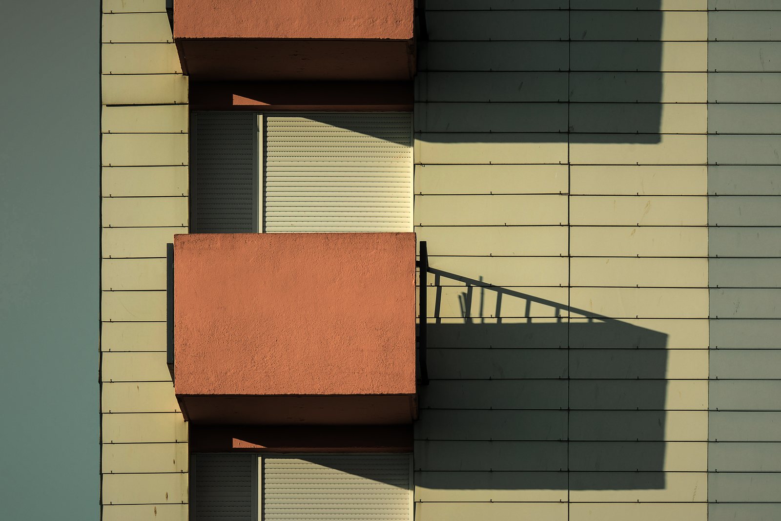 Balcons en saillie de couleur terre cuite sur une façade claire, avec leur ombre portée, photo d'illustration