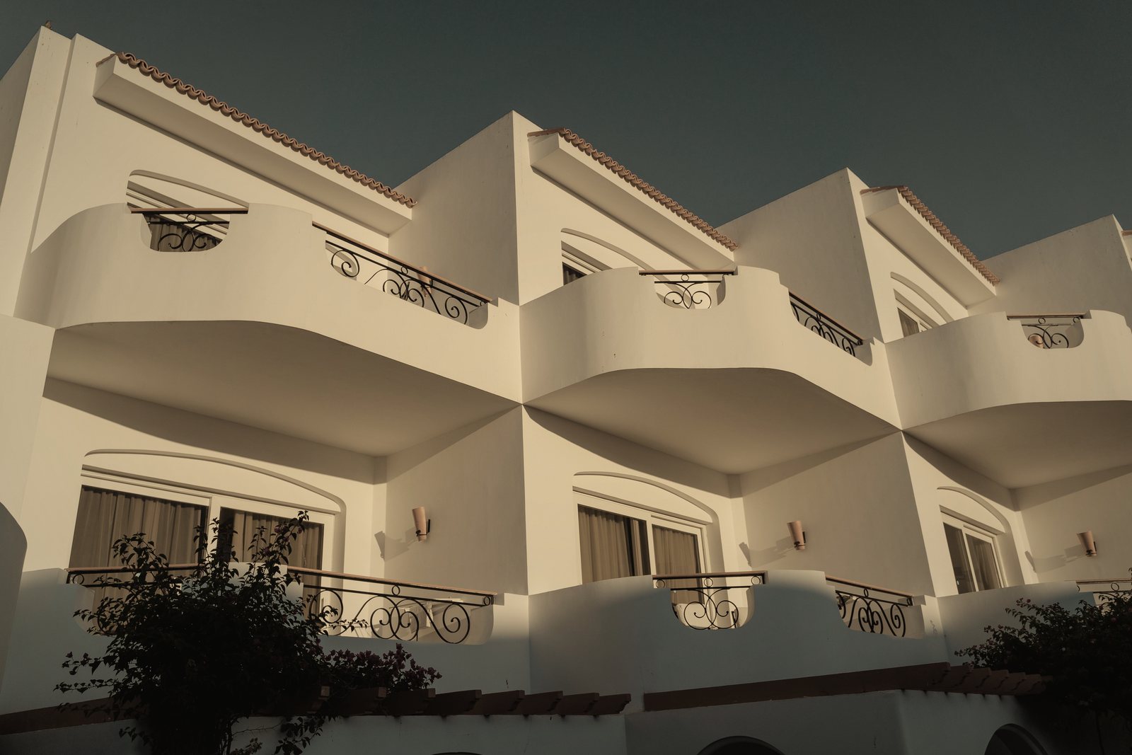 Façade blanche à balcons arrondis en gradins et garde-corps en fer forgé, photo d'illustration