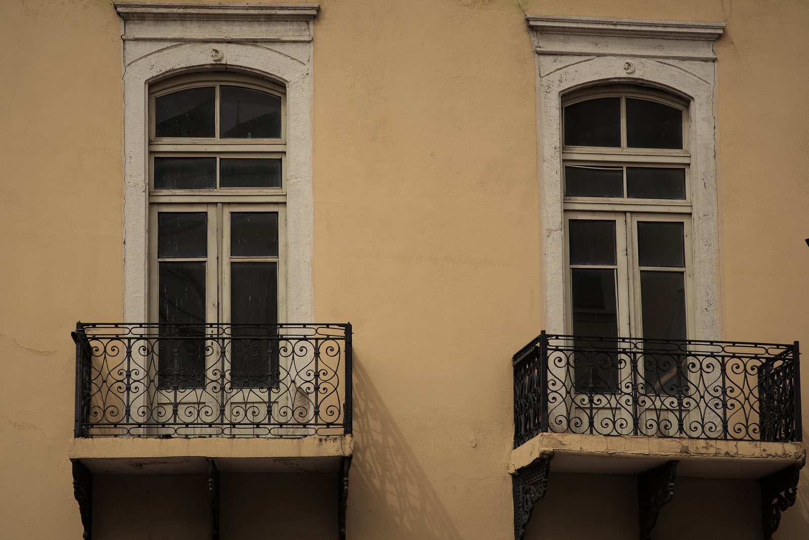 Deux balconnets en fer forgé sous des portes-fenêtres cintrées, façade enduite ocre, photo d'illustration