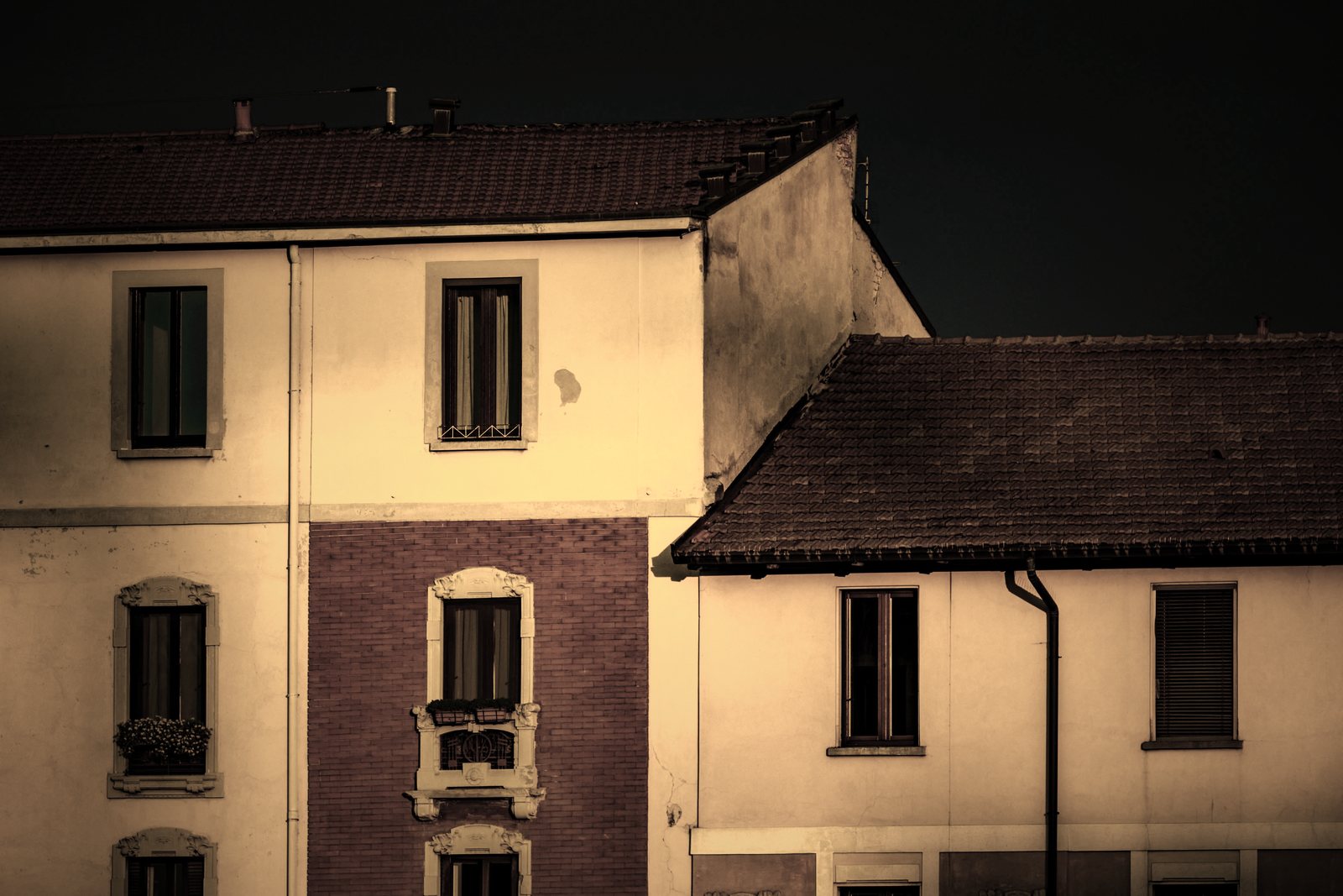 Maisons enduites ocre à toitures de tuiles en pente, éclairées par le soleil couchant, photo d'illustration